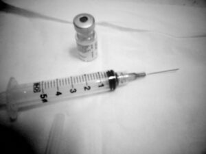 Black and white photo of syringe and vial.