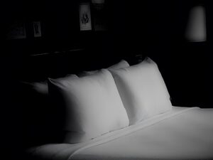 Black and white photo of hotel bed.