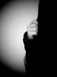 Black and white photo of hand holding side of hood.