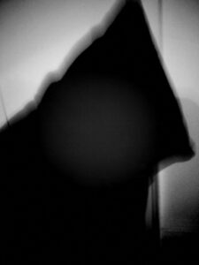 Black and white photo of hooded figure.