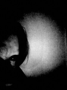 Black and white photo/self portrait of half of my face. One eye is shown and glistening black.