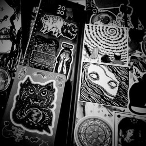 Black and white photo of sketchbooks covered in stickers.