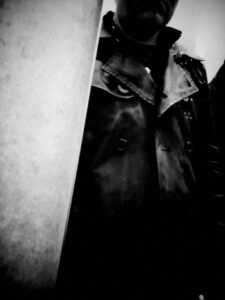 Black and white photo self portrait wearing trench coat.