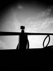 Black and white photo of bridge girder against a cloudy sky.