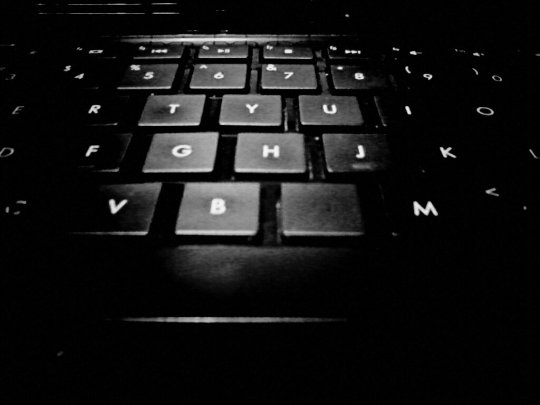 Black and white close up photo of letters on center of black keyboard.