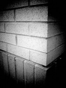 Black and white photo of corner of a building brickwork.