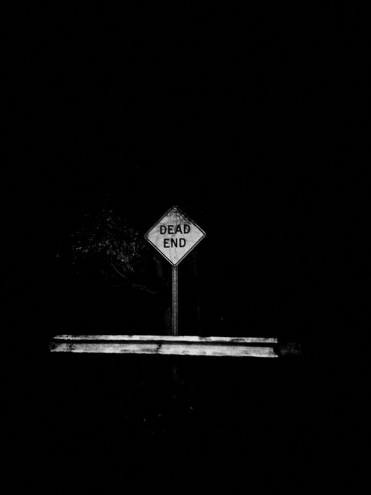 Black and white photo of Dead End street sign with railing.