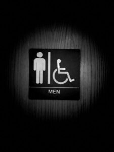 Black and white photo of men's room/restroom sign on wood door.