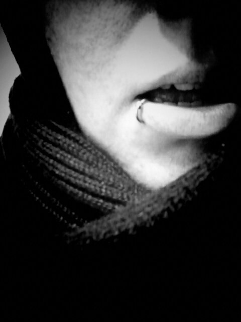 Black and white photo/self portrait of myself wearing a scarf and lip piercing with a slightly open mouth.