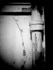 Black and white photo of pipe with cracks and peeling paint.