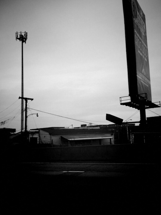 Black and white photo of road sign on side of freeway.