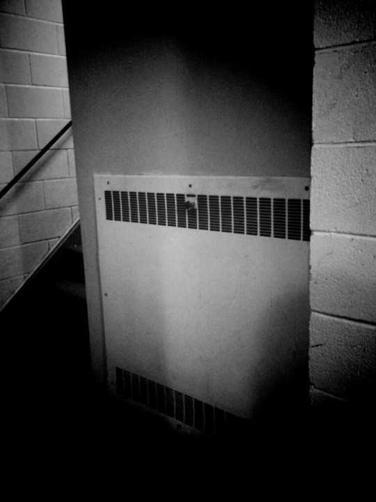 Black and white photo of HVAC vent panel in warehouse.