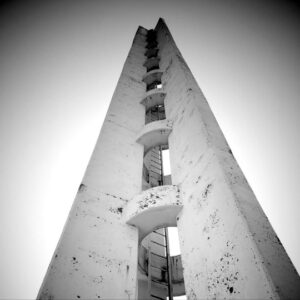 Black and white photo of looking up at a bell tower toward the sky.