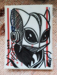 Photo of portrait of a cat shaped helmet with big eyes, neck and part of hoodie drawn in marker on a sticker.